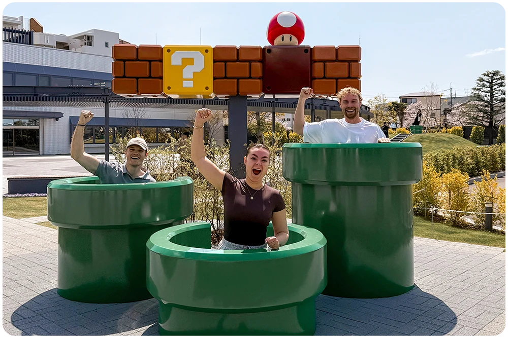 Bezoekers poseren bij Super Mario decor met groene pijpen en vraagtekenblok in Kyoto, Japan