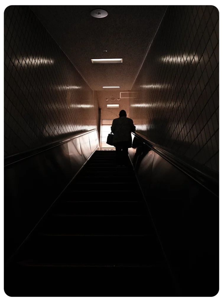 Persoon op een donkere roltrap in een metrostation in Japan met minimalistische en sfeervolle verlichting