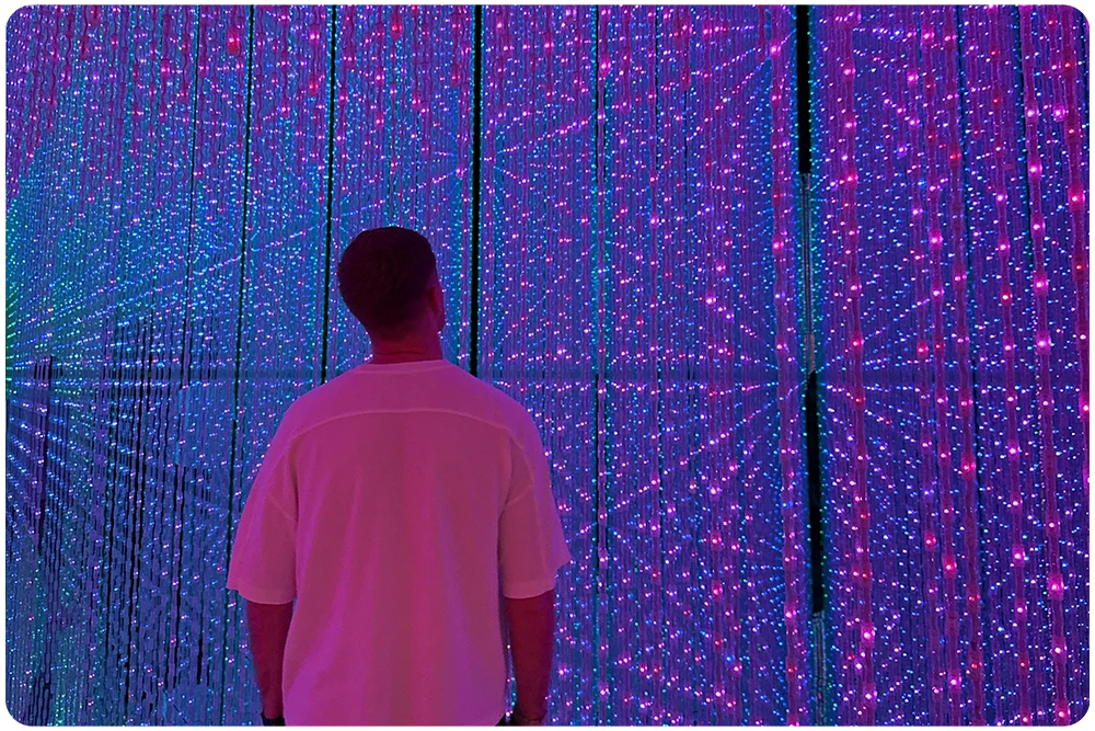 Bezoeker in interactieve lichtinstallatie van teamLab Planets in Tokyo, Japan met kleurrijke LED-verlichting en spiegels
