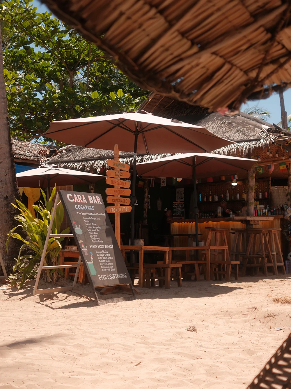 Cara Bar op Nacpan Beach op de Filipijnen met een krijtbord menu, houten barkrukken en een rieten dak direct op het zand