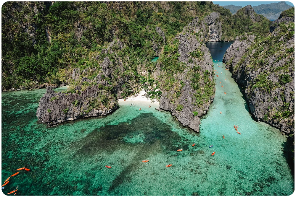 Filipijnen Luchtfoto van de Big Lagoon in El Nido, Filipijnen met oranje kajaks, bangka boten en helder turkoois water tussen kalkstenen rotswanden