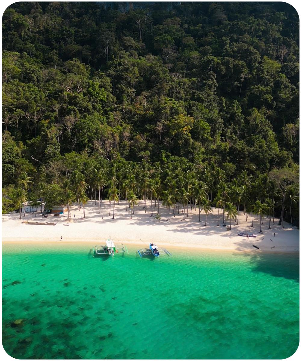 Luchtfoto van een wit strand met turkoois water en twee bangka boten tijdens Tour A in El Nido, Filipijnen
