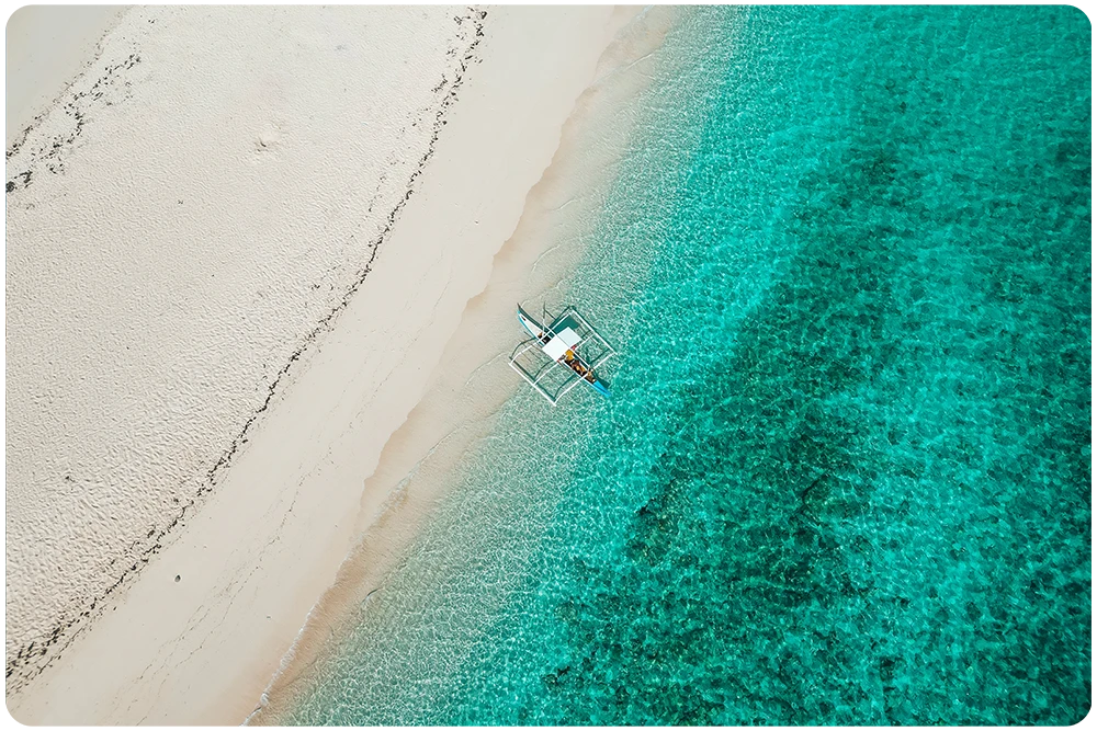 Dronefoto van een tropisch strand met turquoise water en traditionele boot in de Filipijnen