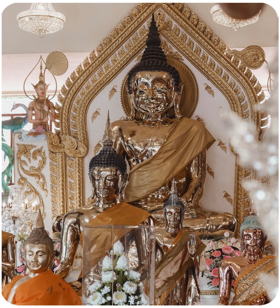 Gouden Boeddhabeelden in een tempel in Bangkok, Thailand met goudkleurige ornamenten, bloemen en kristallen kroonluchters op de achtergrond