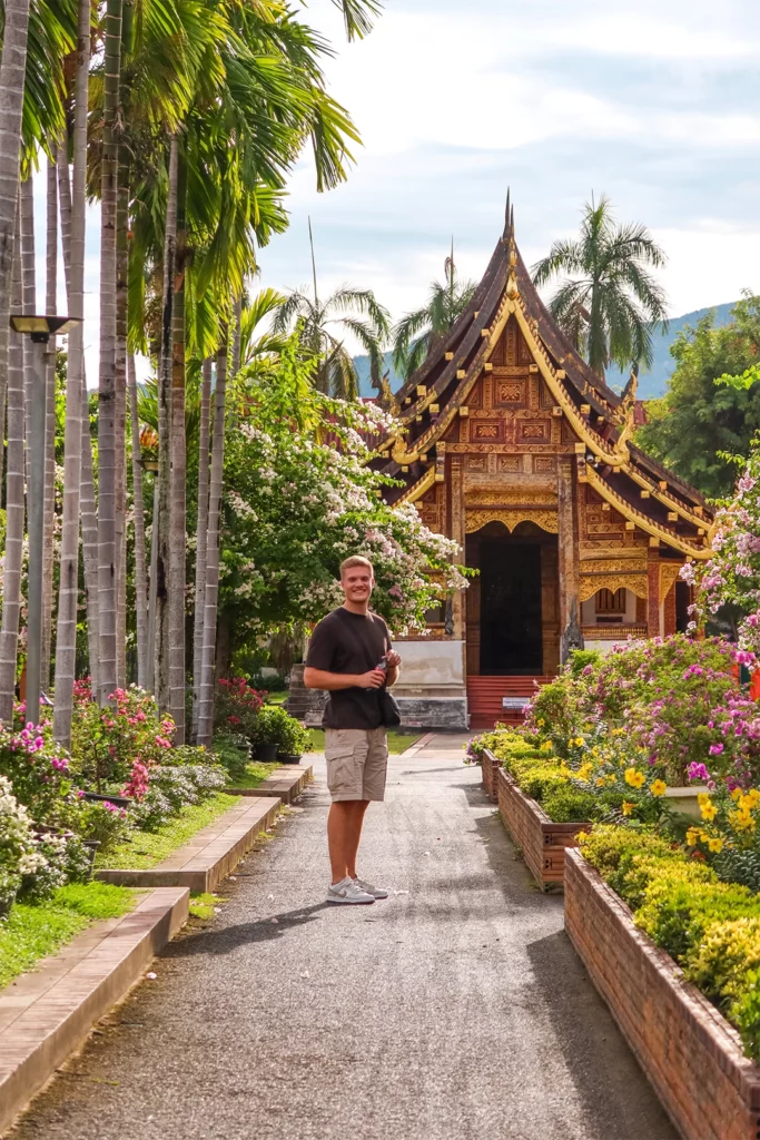 Tempel met een versierde houten gevel tussen palmbomen in Chiang Mai