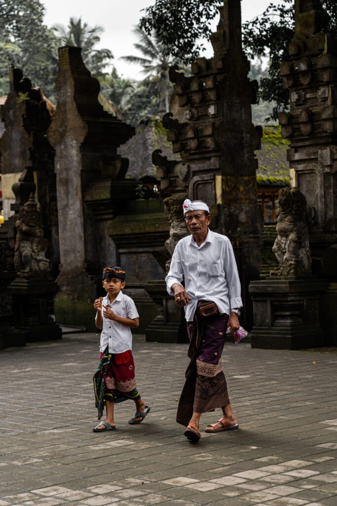 Man en kind in traditionele kleding bij de Tirta Empul-tempel op Bali