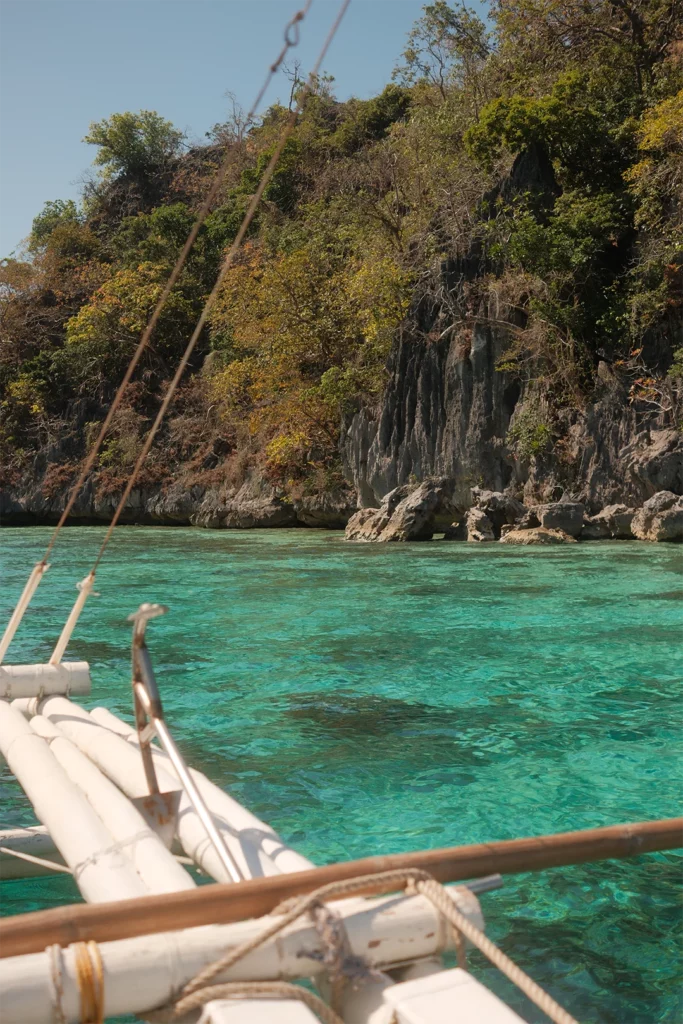 Helder turquoise water tussen kalkstenen rotsen bij Coron