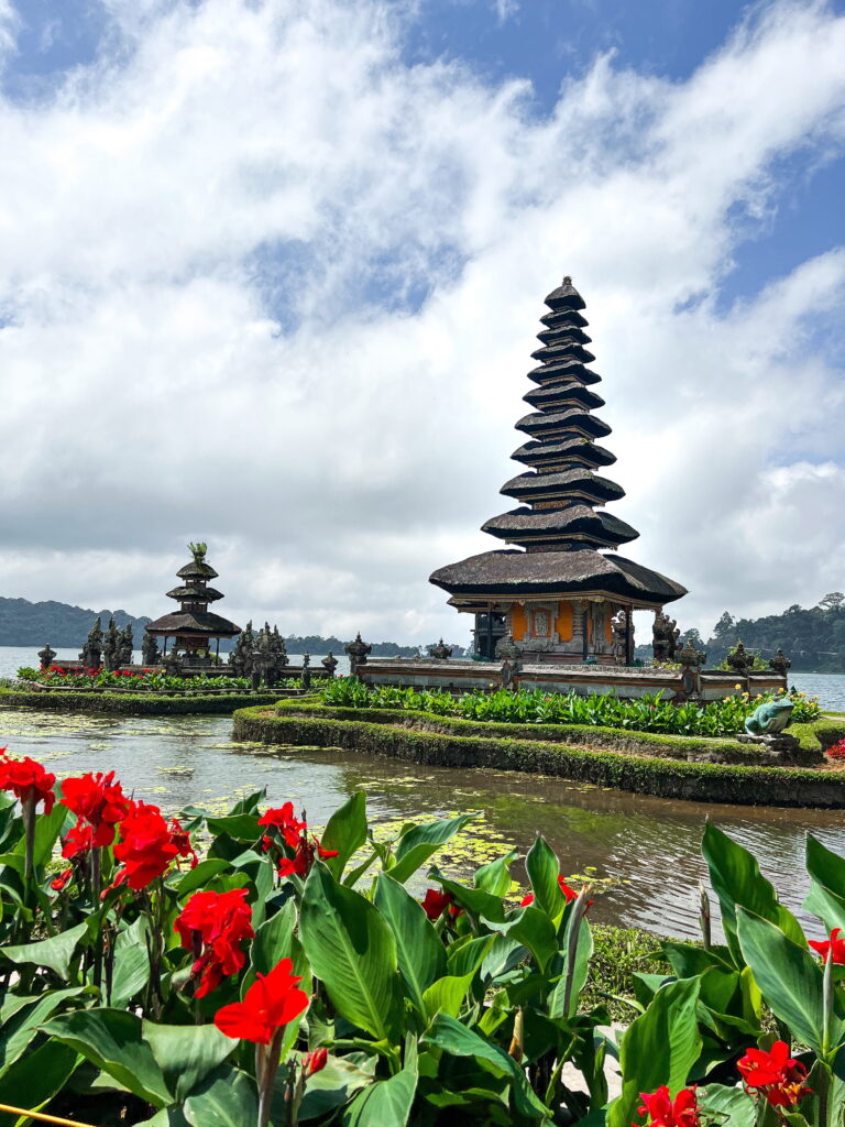 Tempeltoren aan het water met bloemen op de voorgrond op Bali