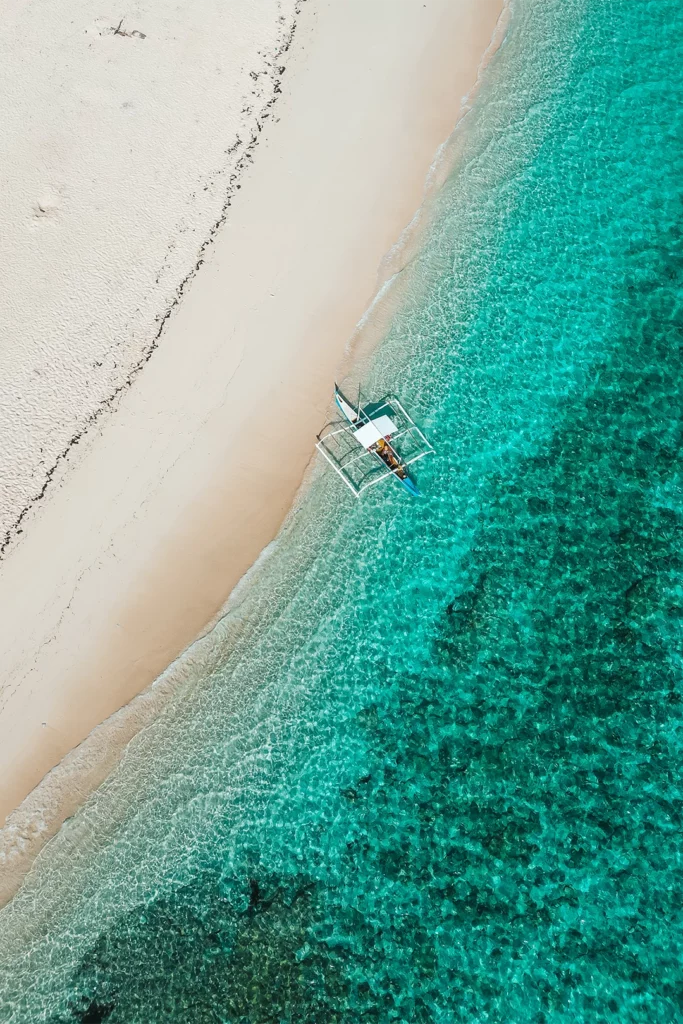 Luchtfoto van een boot bij een wit strand op Siargao