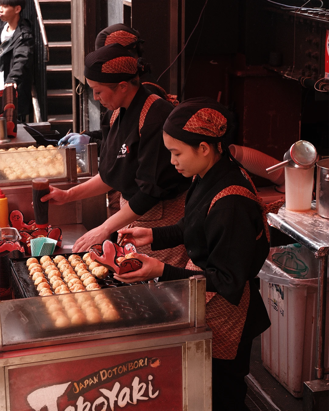 Koks bereiden takoyaki bij een eetkraam in Dotonbori, Osaka