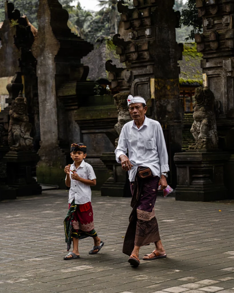 Volwassene en kind in traditionele kleding bij een tempel op Bali