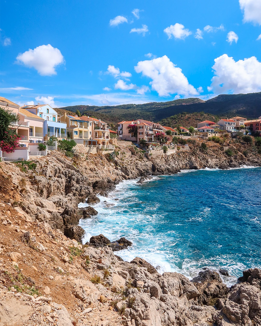 Kleurrijke huizen boven een rotsachtige baai op Kefalonia