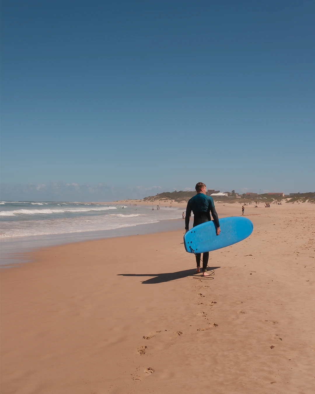 Surfer met surfplank op het strand van Jeffreys Bay in Zuid-Afrika