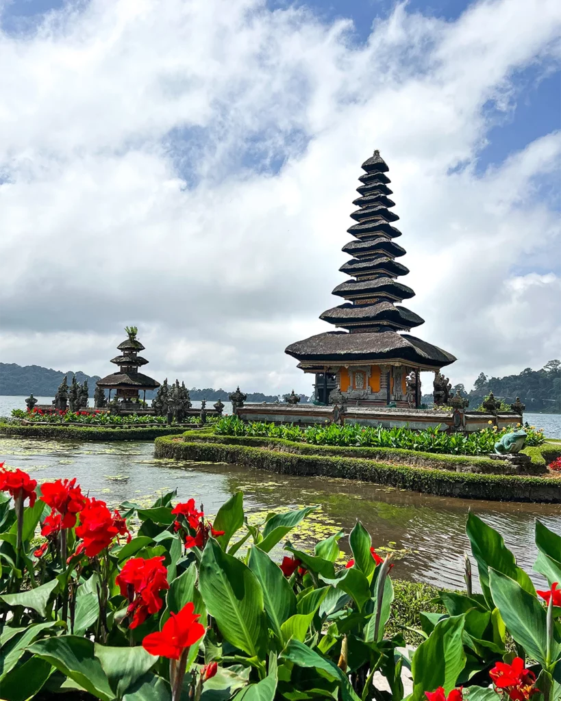 Tempeltoren bij het water met bloemen op de voorgrond op Bali